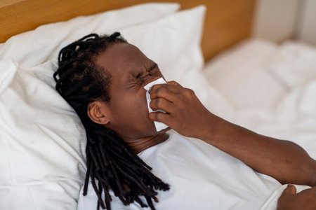 Closeup Shot Of Sick Black Man Blowing Runny Nose In Napkinの写真素材