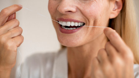 Toothcare and oral treatment concept. Closeup cropped view of unrecognizable middle aged woman using dental flossの写真素材