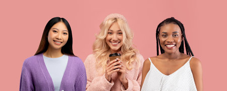 Three multiracial girlfriends posing on pink studio background