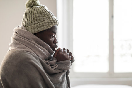 African american guy freezing in house in winter, copy spaceの写真素材