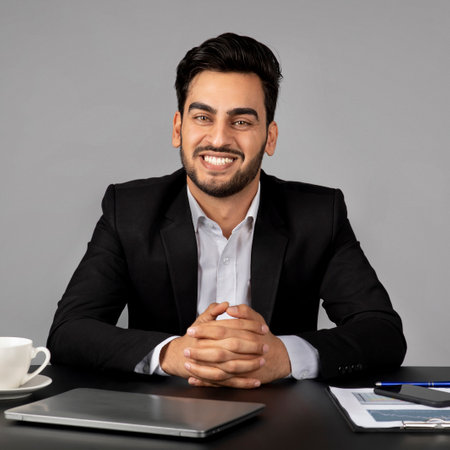 Portrait Of Handsome Arab Businessman Sitting At Desk And Smiling At Cameraの写真素材