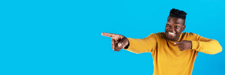 Check This. Cheerful black guy pointing aside at copy space with two hands