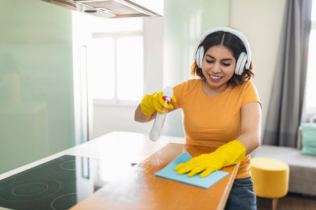 Happy Middle Eastern Female Cleaning Kitchen Counter With Detergent Spray And Ragの写真素材