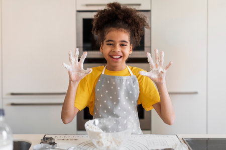 Black Girl Showing Sticky Hands Full Of Dough While Baking In Kitchenの写真素材