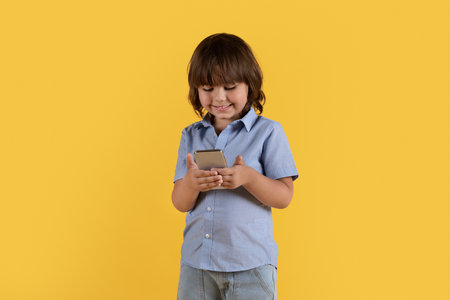 Great app for kids. Interested little boy looking at smartphone screen, enjoying educational content online and smilingの写真素材