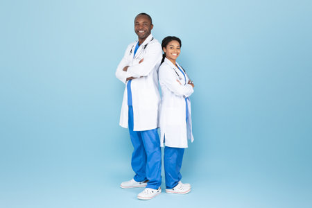 Mature african american doc man and woman posing with folded arms, experienced doctors wearing lab coatsの写真素材