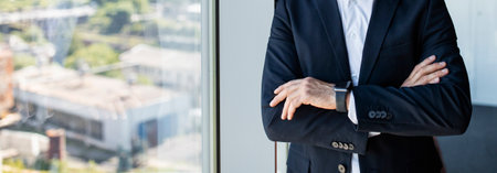 Unrecognizable confident mature businessman with folded arms standing in office near window, panorama, copy spaceの写真素材