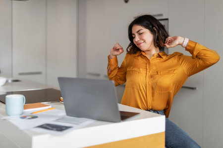 Young smiling arab woman stretching after working day at home officeの写真素材