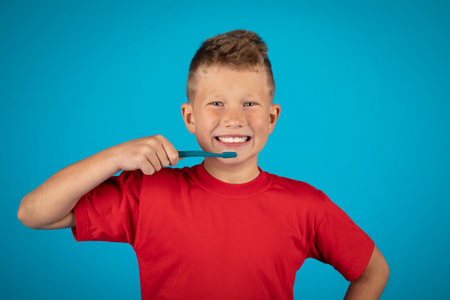 Happy Preteen Boy Brushing Teeth With Toothbrush And Smiling At Camera