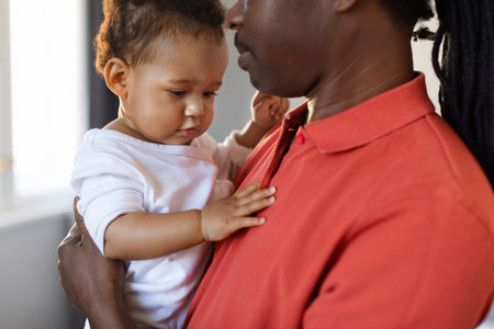 Fathers Love. Young Black Man Holding Cute Infant Son In Handsの写真素材