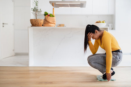 Sad millennial african american woman in casual crying on scales, suffering from excess weightの写真素材