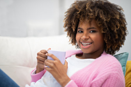 Happy african american woman chillng at home, drinking coffee