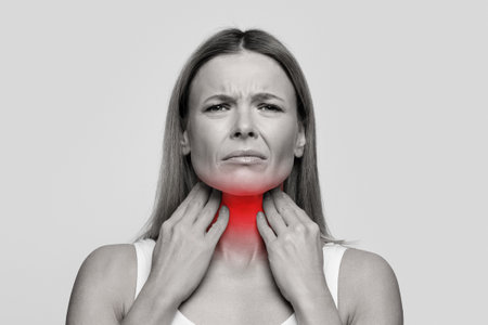 Woman suffering from sore throat, touching her neckの写真素材