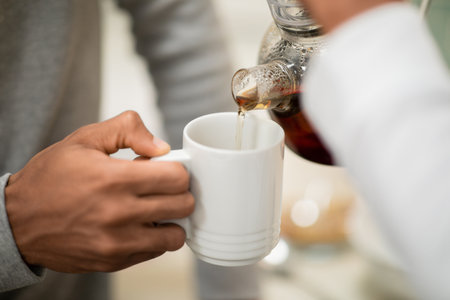 Hands of black woman pouring black tea for her husband