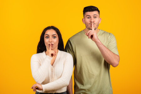 Cheerful inspired pretty young arabic woman and guy in casual put finger to lips, make shhh signの写真素材