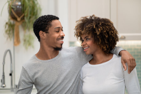 Handsome happy african american husband hugging wife at home