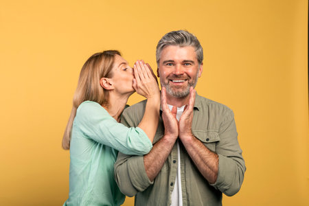 Gossip, share advice. Woman whispering to her husband on ear, happy surprised man listening wifeの写真素材