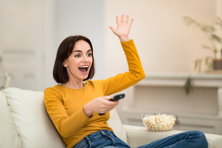 Emotional woman watching TV show with popcorn at home