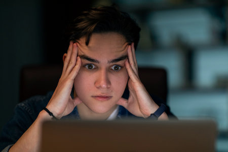 Closeup of stressed young man looking at laptop screen