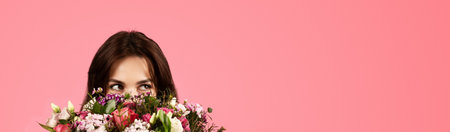 Smiling young caucasian lady enjoy aroma of bouquet of flowers, rejoices at gift, isolated on pink backgroundの写真素材