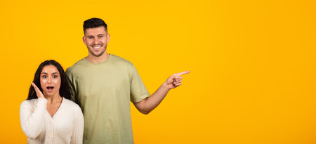 Cheerful shocked young arabic couple in casual with open mouth point finger at empty spaceの写真素材