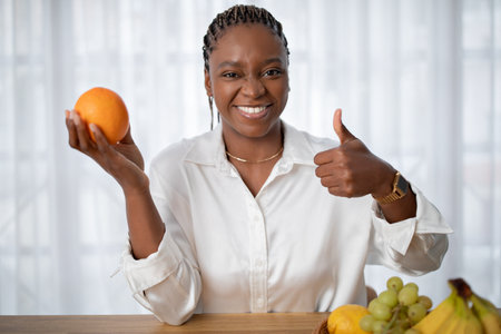 Positive good-looking black lady showing orange and thumb upの写真素材