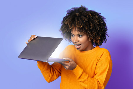 Surprised african american woman open laptop and looking at sceenの写真素材