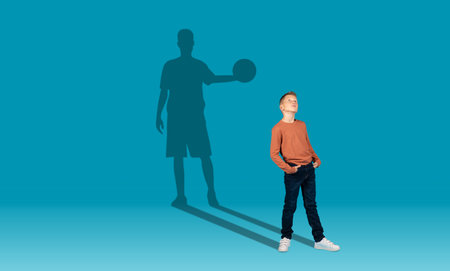 Boy and shadow of sportive male basketball player on wallの写真素材