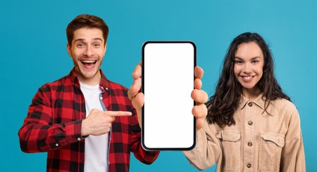 Mobile App. Joyful Young Man And Woman Pointing At Empty Cellphone