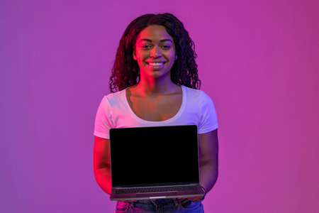 Cool Website. Smiling Young Black Woman Holding Laptop Computer With Blank Screenの写真素材