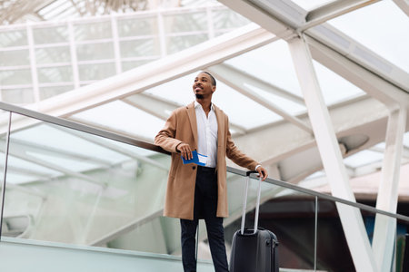 Smiling Young African American Man Standing With Suitcase At Airportの写真素材