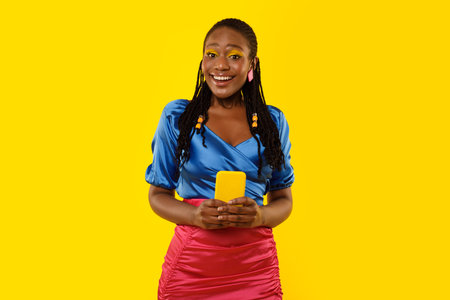 Happy Black Female Using Phone Standing On Yellow Studio Background