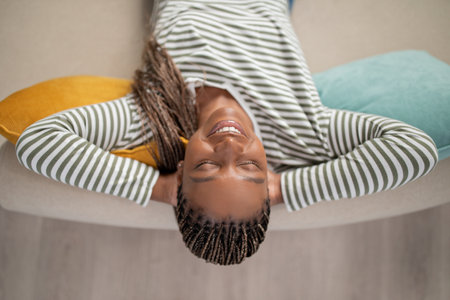 Happy young black woman chilling on couch at home, closeup