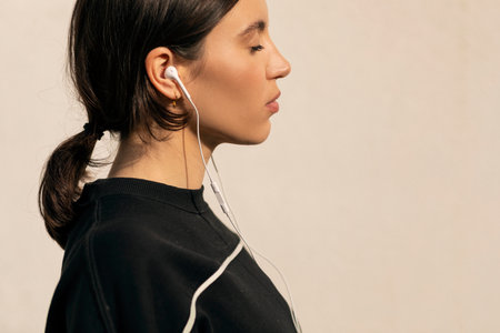 Calm caucasian millennial woman in sportswear and headphones with closed eyes enjoys fitness