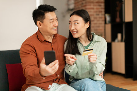 Banking application and e-commerce concept. Excited asian spouses using smartphone and credit card,...