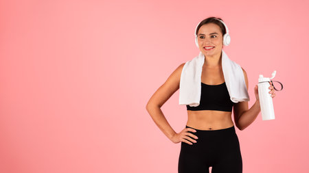 Sporty Lifestyle Concept. Happy young woman in wireless headphones holding fitness bottle