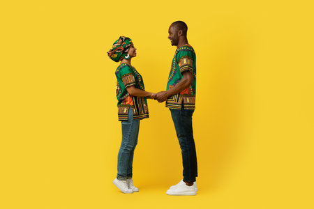 Loving black couple in national costumes bonding on yellowの写真素材