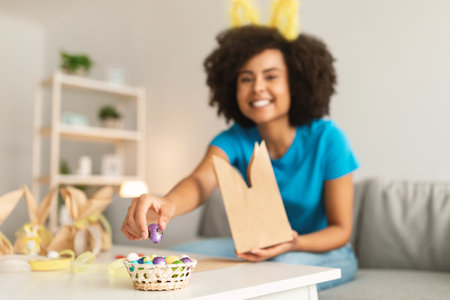 Easter Treats. Black Woman Packing Chocolate Eggs Into Paper Bag At Homeの写真素材