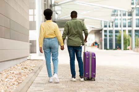 Black Couple Walking Holding Hands At Airport Outside, Back Viewの写真素材