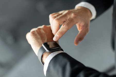 Smart devices. Unrecognizable businessman pressing blank screen on smartwatch on his hand, cropped, mockupの写真素材