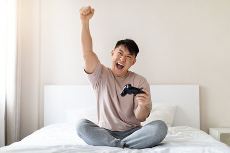 Happy emotional asian man playing video games at homeの写真素材
