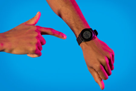 Black man in neon with smartwatch on handの写真素材
