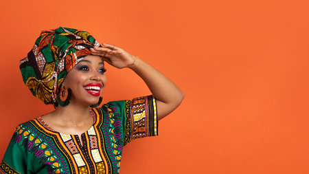 Cheerful black woman in african costume looking at copy space