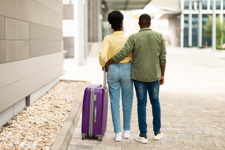 Rear View Of African Couple Walking With Travel Suitcase Outsideの写真素材