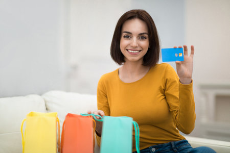 Cheerful brunette woman with shopping bags and credit cardの写真素材