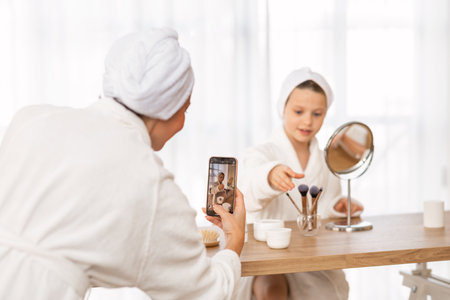 Sharenting Concept. Mother Taking Photo Of Her Daughter Doing Makeup At Homeの写真素材