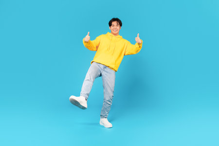 Asian Male Teen Gesturing Thumbs Up With Both Hands, Studio
