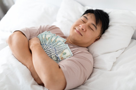 Happy sleeping chinese man hugging bunch of cashの写真素材