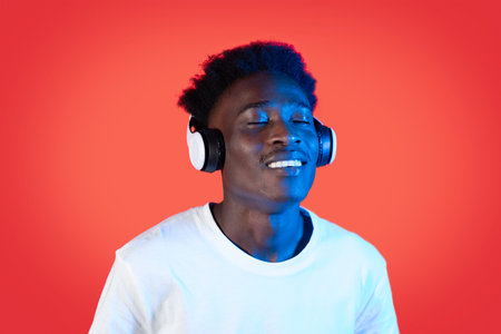 Joyful black guy hipster listening to music, using wireless headphonesの写真素材