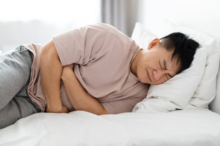 Man lying in bed and suffering from stomach painの写真素材